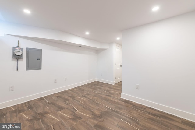 basement featuring electric panel and dark hardwood / wood-style flooring