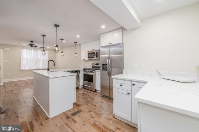 kitchen with kitchen peninsula, light wood-type flooring, stainless steel appliances, ceiling fan, and white cabinetry