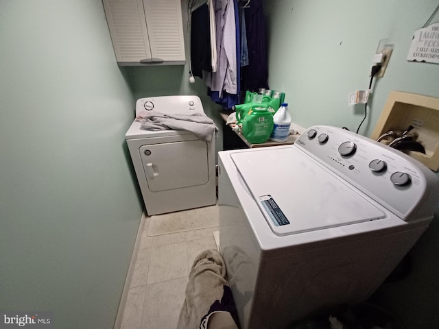 laundry room featuring cabinets, washing machine and dryer, and light tile patterned flooring