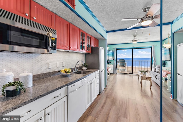 kitchen with dishwasher, sink, light wood-type flooring, a textured ceiling, and tasteful backsplash