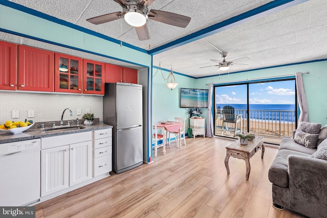 kitchen with backsplash, white dishwasher, sink, stainless steel fridge, and light hardwood / wood-style floors