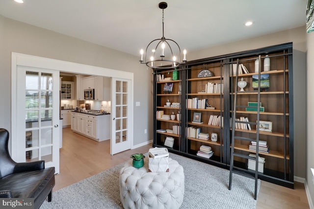 living area with light hardwood / wood-style flooring, a chandelier, and french doors