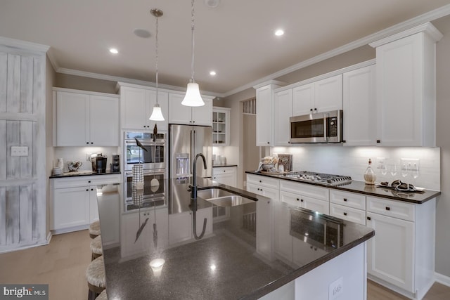 kitchen featuring a large island with sink, sink, hanging light fixtures, white cabinetry, and stainless steel appliances