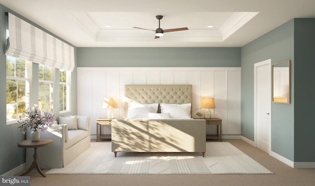 carpeted bedroom with ceiling fan and a tray ceiling