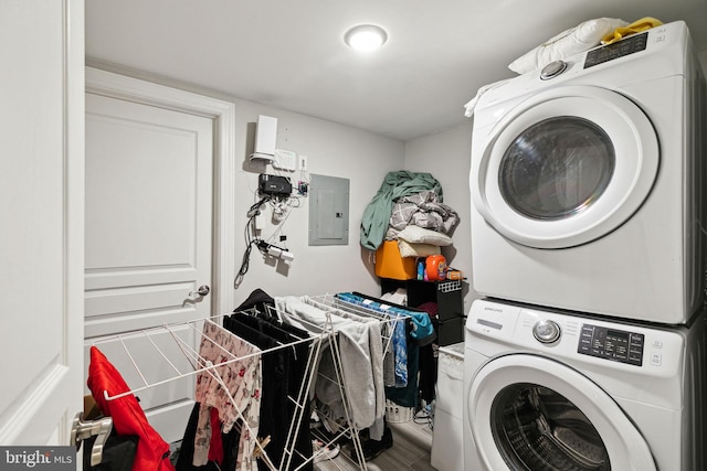 laundry area featuring stacked washer / drying machine, electric panel, and hardwood / wood-style floors