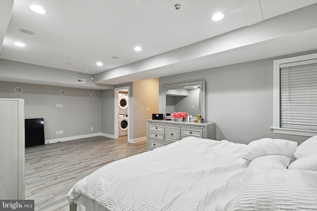 bedroom with light hardwood / wood-style floors and stacked washer / dryer