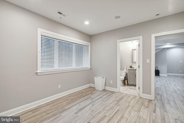 unfurnished bedroom featuring connected bathroom, a walk in closet, light hardwood / wood-style floors, and a closet