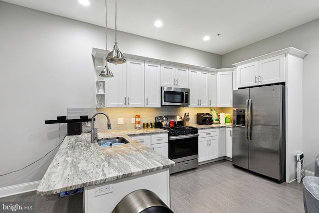 kitchen featuring sink, decorative light fixtures, appliances with stainless steel finishes, kitchen peninsula, and white cabinets