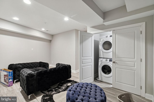 laundry room with stacked washer and clothes dryer and light wood-type flooring