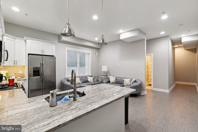 kitchen featuring sink, white cabinetry, hanging light fixtures, stainless steel appliances, and light stone countertops