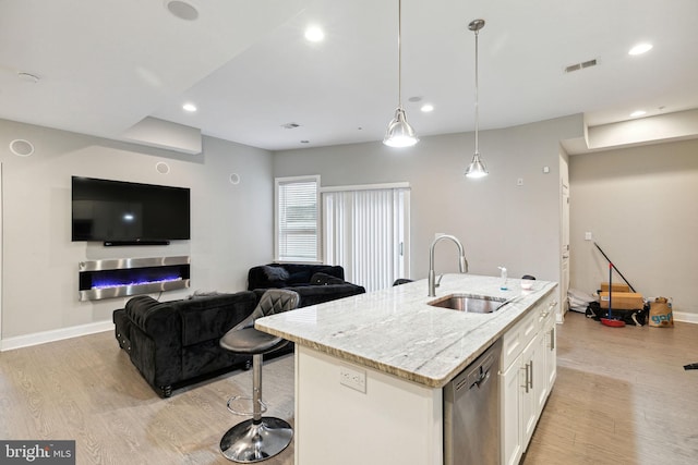 kitchen with white cabinetry, dishwasher, sink, hanging light fixtures, and a kitchen island with sink