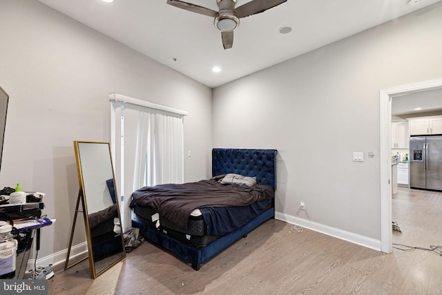 bedroom with ceiling fan, light hardwood / wood-style floors, and stainless steel fridge with ice dispenser