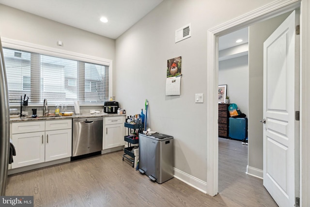 kitchen featuring white cabinetry, stainless steel dishwasher, and light wood-type flooring