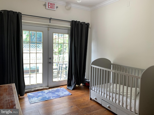 bedroom featuring french doors, a nursery area, ornamental molding, and hardwood / wood-style floors