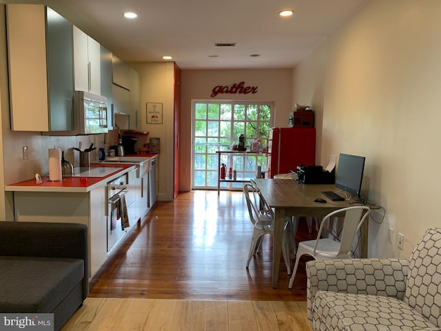 kitchen featuring white cabinets, tasteful backsplash, stainless steel appliances, and light hardwood / wood-style flooring