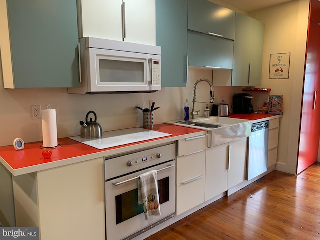 kitchen with white cabinets, light wood-type flooring, sink, and appliances with stainless steel finishes