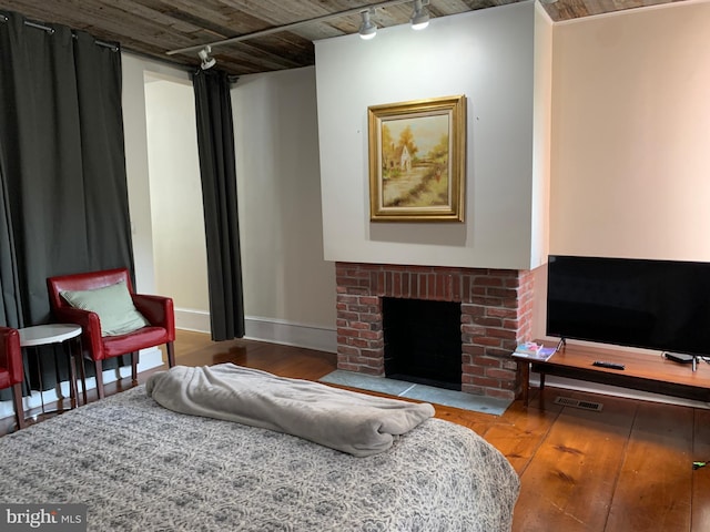 living room featuring hardwood / wood-style floors, rail lighting, and a brick fireplace