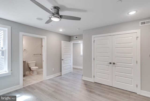 unfurnished bedroom with ceiling fan, a closet, ensuite bathroom, and light wood-type flooring