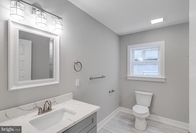 bathroom with toilet, vanity, and hardwood / wood-style flooring