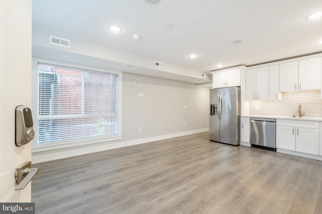 kitchen featuring white cabinets, plenty of natural light, light hardwood / wood-style floors, and stainless steel appliances