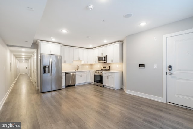 kitchen featuring decorative backsplash, light hardwood / wood-style flooring, white cabinets, and appliances with stainless steel finishes