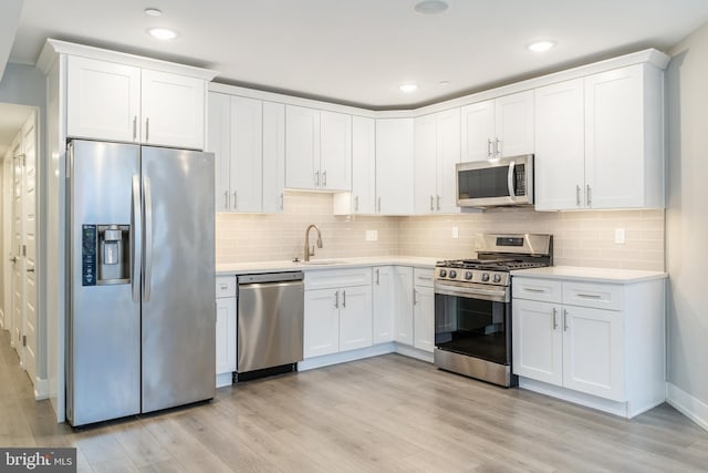 kitchen with white cabinetry, sink, stainless steel appliances, and light hardwood / wood-style floors