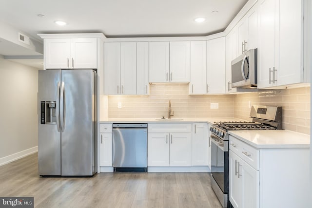 kitchen with light wood-type flooring, white cabinetry, sink, and appliances with stainless steel finishes