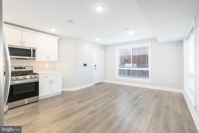 kitchen with decorative backsplash, light wood-type flooring, white cabinetry, and stainless steel appliances