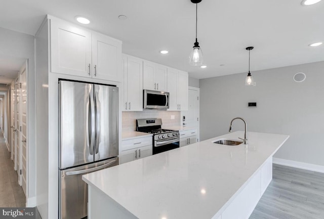 kitchen with sink, decorative light fixtures, a kitchen island with sink, white cabinets, and appliances with stainless steel finishes