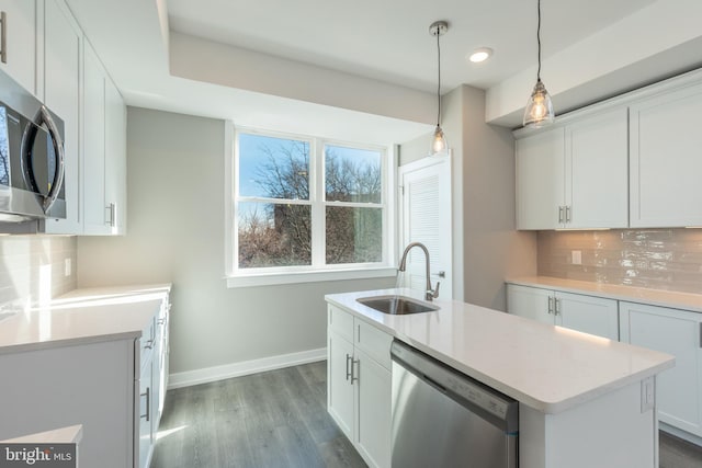 kitchen featuring stainless steel appliances, white cabinetry, a kitchen island with sink, and sink