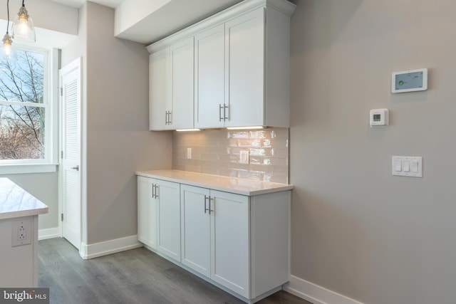 kitchen with backsplash, light hardwood / wood-style floors, white cabinetry, and hanging light fixtures