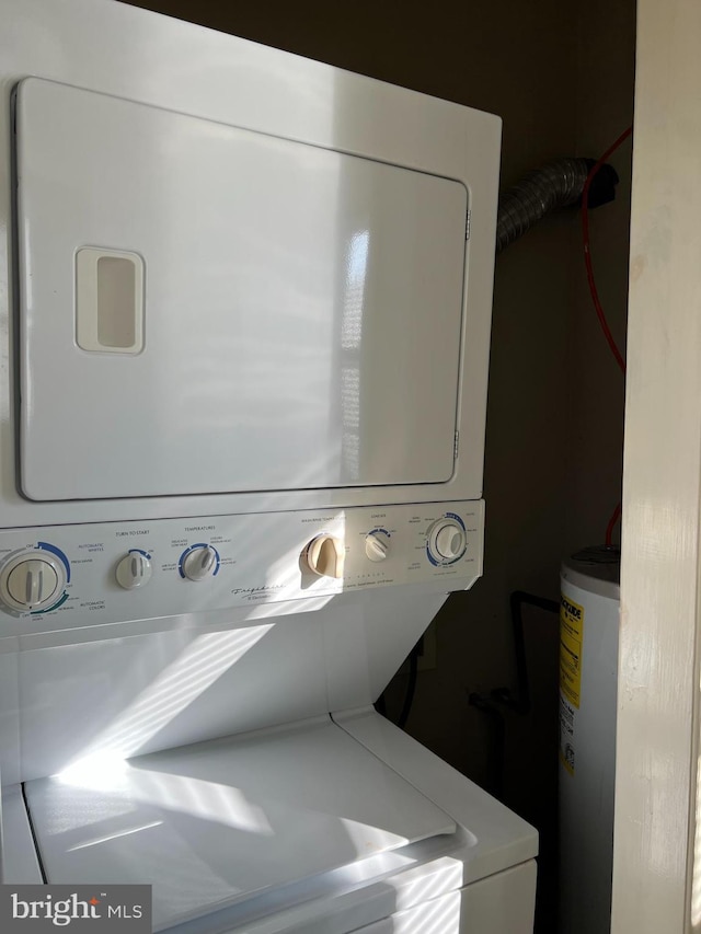 clothes washing area featuring water heater and stacked washer and clothes dryer