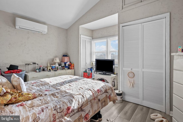 bedroom featuring light wood-type flooring, an AC wall unit, and vaulted ceiling