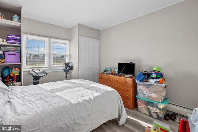 bedroom featuring a closet, a baseboard radiator, and wood-type flooring