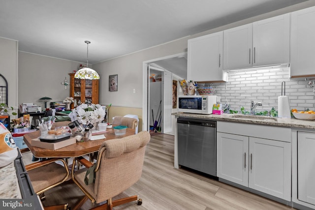 kitchen with stainless steel dishwasher, white cabinets, and light stone counters