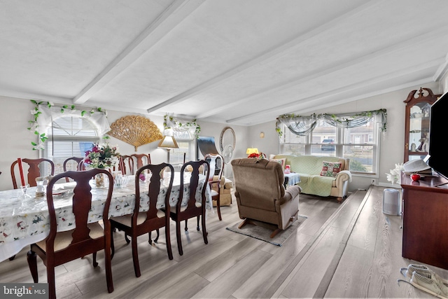 dining room with beamed ceiling, light wood-type flooring, and a wealth of natural light