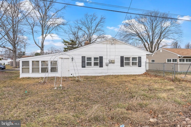 back of house featuring a lawn and a sunroom