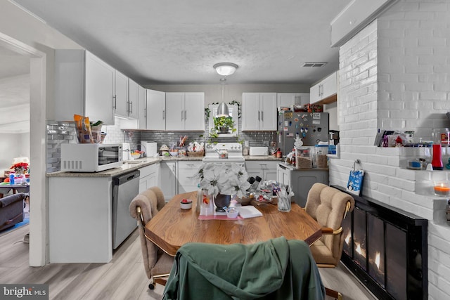 kitchen featuring appliances with stainless steel finishes, backsplash, a textured ceiling, light hardwood / wood-style floors, and white cabinetry