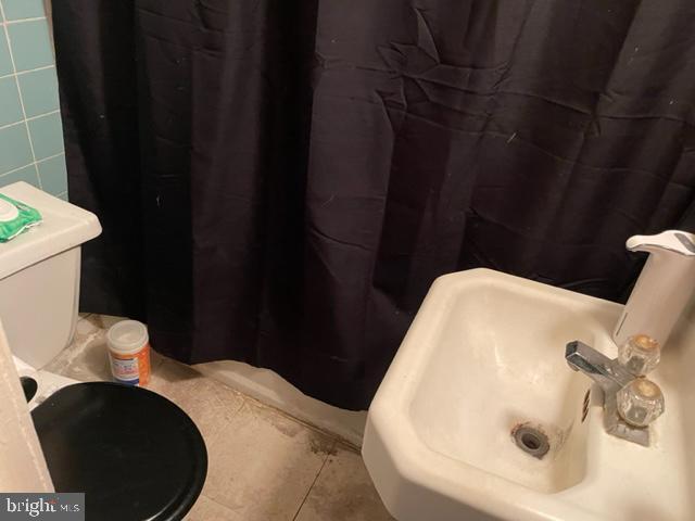 bathroom featuring tile patterned floors, sink, tile walls, and toilet