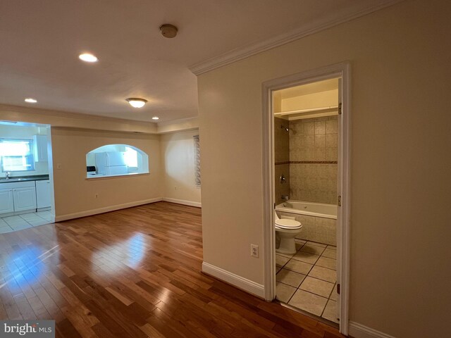 interior space with connected bathroom, hardwood / wood-style flooring, and ornamental molding