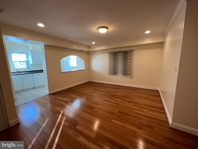 unfurnished room with sink, dark wood-type flooring, and ornamental molding