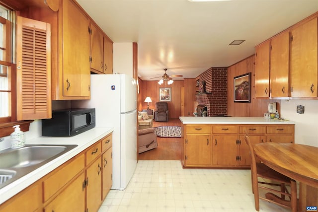 kitchen with a fireplace, sink, wood walls, kitchen peninsula, and ceiling fan