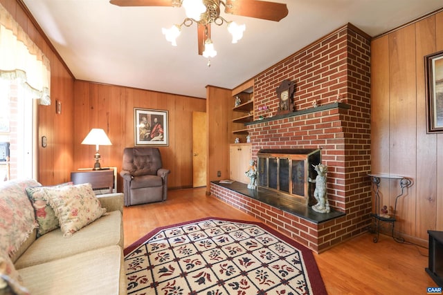 living room featuring ceiling fan, built in features, wooden walls, and a fireplace