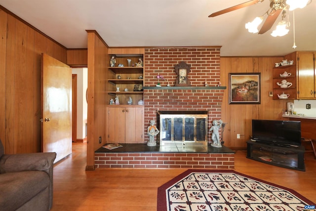 living room featuring ceiling fan, a brick fireplace, wood walls, hardwood / wood-style floors, and built in shelves