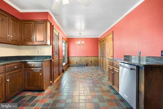 kitchen with hanging light fixtures, stainless steel dishwasher, wooden walls, ceiling fan with notable chandelier, and ornamental molding