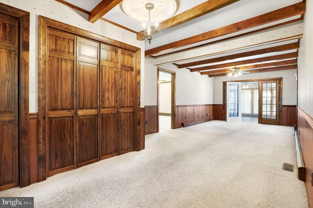 carpeted spare room featuring wood walls, french doors, and beamed ceiling