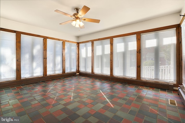 unfurnished sunroom featuring a wealth of natural light and ceiling fan