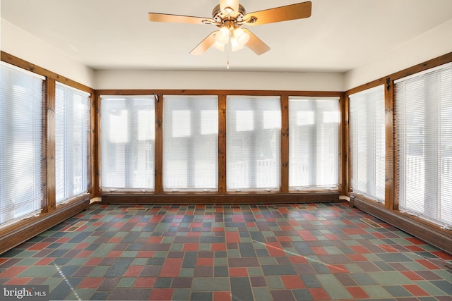 unfurnished sunroom featuring ceiling fan and a healthy amount of sunlight