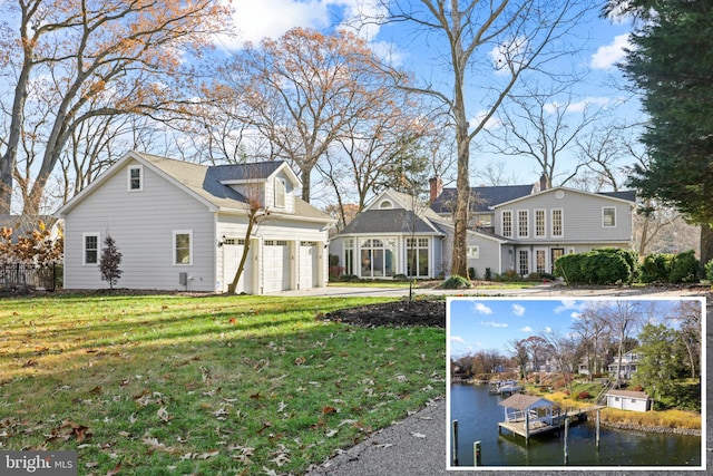 back of house featuring a yard, a water view, and a garage