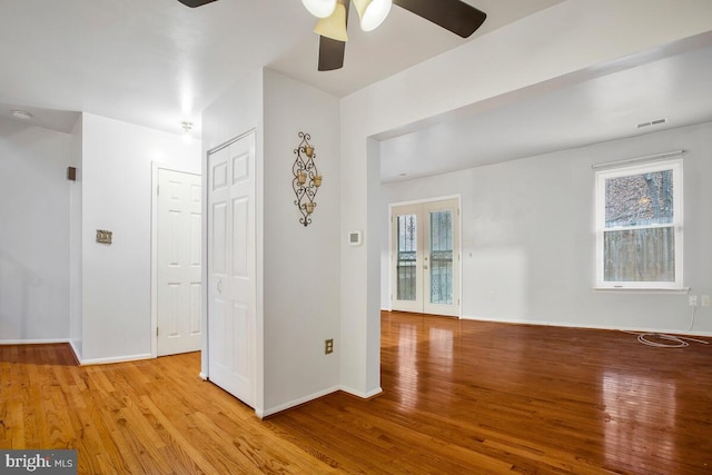 empty room featuring ceiling fan, light wood-type flooring, and french doors